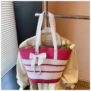 Detalle de bolso de paja a rayas rosas y blancas con colgante de lazo de perlas y flores