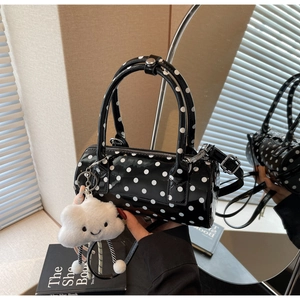 Close-up of black polka dot cylinder bag with glossy finish and plush cloud charm