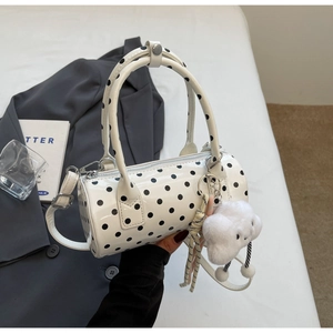 Close-up of a white polka dot cylinder handbag with a plush cloud pendant detail