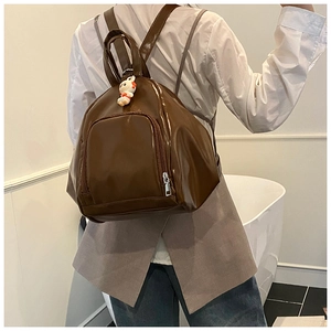 Detail of glossy brown backpack with smooth PU texture and white rabbit plush charm