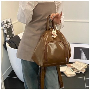 Detail of dark brown glossy backpack with a cute rabbit pendant on the zipper pocket