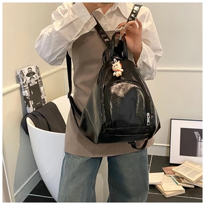 Macro shot of glossy black patent leather backpack texture with a cute white cat pendant