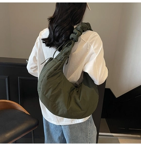 Close-up of large dark green quilted crescent bag with adjustable drawstring shoulder strap