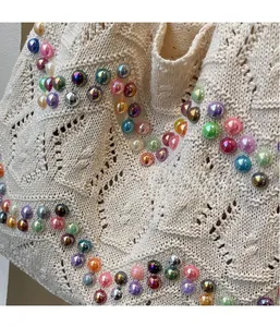 Close-up of beige hollow knit tote bag featuring colorful iridescent beads and textures