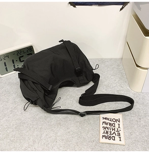 Detailansicht der schwarzen Nylon-Tasche mit verstellbarem Gurt und Schnalle auf Grau