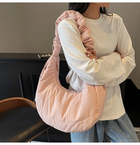 Close-up of pink quilted crescent bag with textured bubble fabric and ruffled shoulder strap