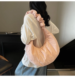 Detail of soft pink crescent shoulder bag with quilted texture and ruched cloud strap