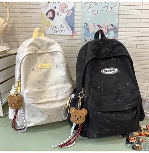 Detalle de mochilas escolares con diseño de mármol, ositos de peluche y parches RKDBAG