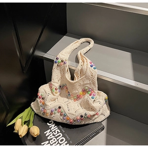 Close-up of beige knit tote bag with colorful beadwork and bohemian crochet texture