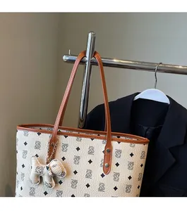 Dettaglio della borsa tote beige con stampa orso, spalline sottili in pelle e ciondolo
