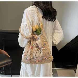 Detail of hand-crocheted beige tote bag featuring colorful bead accents and a soft knit texture