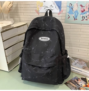 Primer plano de mochila de lona con patrón de mármol negro y logo RKDBAG en un escritorio