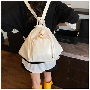 Detail view of white glossy patent leather backpack with a cute astronaut charm on zippers