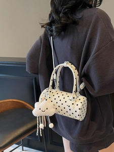 Polka dot cylinder shoulder bag with cute cloud charm shown in a stylish crossbody pose