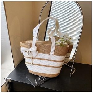 Detalle de bolso playero a rayas con lazo de gasa blanco y colgante de perlas