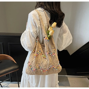 Detail of beige hollow knit tote bag with colorful beads and floral accent