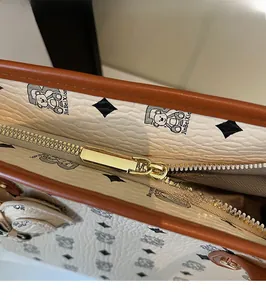 Dettaglio della cerniera dorata sulla borsa tote beige con motivo monogramma e pelle