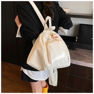 Side view of a white patent leather triangular backpack with astronaut charm on a model