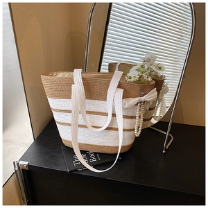 Detalle del bolso de paja a rayas con colgante de lazo de perlas y flor de margarita