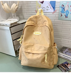Detalle de mochila amarilla con patrón de mármol, etiqueta RKDBAG y bolsillo lateral