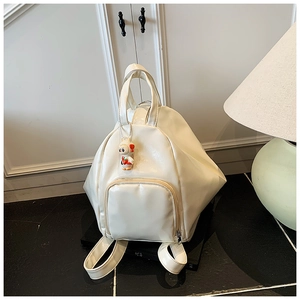 Detail of white PU backpack featuring unique triangular structure and rabbit pendant charm