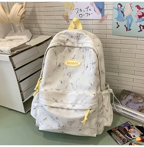 Mochila blanca con estampado de mármol y detalles amarillos sobre escritorio con libros