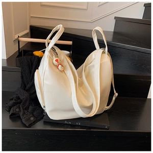 Detail of white large tote bag with side zipper and smooth leather texture on stairs