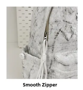 Detail of smooth metal zipper and white drawstring puller on a marble grey backpack