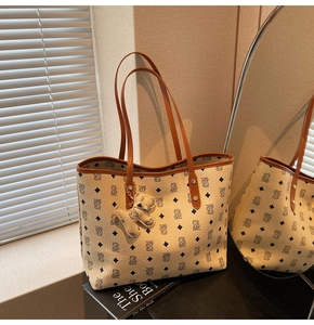 Dettaglio della borsa tote monogramma con trama litchi e ciondolo a forma di cucciolo