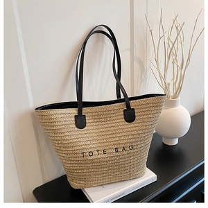 Close-up of beige woven tote bag with black handles and Tote Bag lettering texture