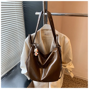 Detail of brown glossy leather tote bag with a cute white bunny pendant on a hanger