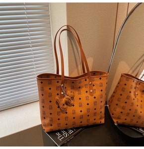 Dettaglio della borsa tote caramello con motivo monogramma e ciondolo vicino allo specchio