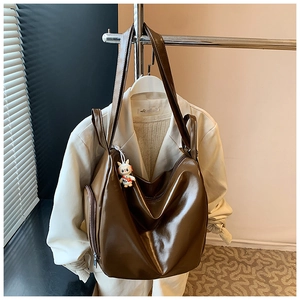 Close-up of a large brown glossy tote bag with a zipper pocket and a rabbit charm