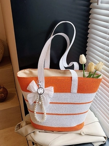 Bolso de paja a rayas naranjas y blancas con lazo grande y colgante de perlas