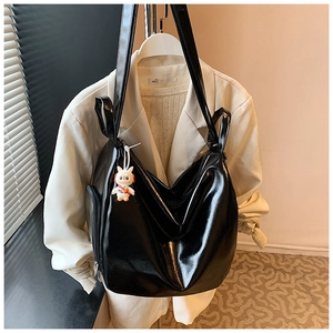Detail of black glossy tote bag featuring a side zipper pocket and cute white rabbit charm