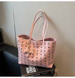 Dettaglio della borsa tote rosa con motivo a trama e ciondolo a cucciolo sul manico