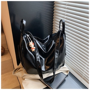 Detail of glossy black tote bag with smooth texture and cute white rabbit charm accessory