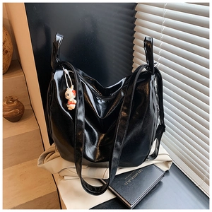 Close-up of black glossy leather shoulder bag with a cute rabbit pendant accessory