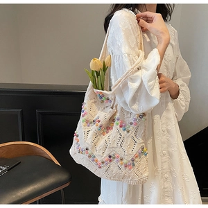 Close-up of beige crochet tote bag featuring colorful pearl bead wave patterns
