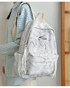Close-up of marble pattern backpack with tassel detail and minimalist brand logo