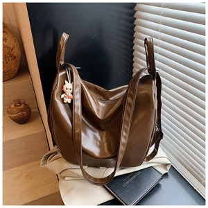 Detail of dark brown glossy PU leather tote bag with a cute cartoon rabbit keychain