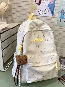 Mochila blanca con estampado de mármol, cremalleras amarillas y amuleto de oso