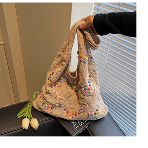 Detail of beige knit tote bag featuring colorful bead accents and thick woven texture
