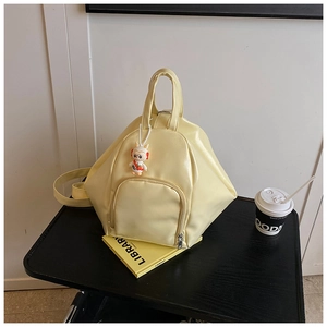 Detail view of cream yellow geometric backpack featuring a cute rabbit charm and front pocket