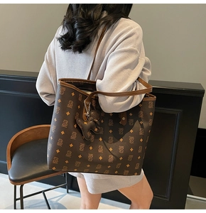 Dettaglio di una grande borsa tote monogramma marrone in pelle con ciondolo a orsetto