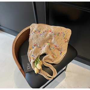 Detail of beige crochet tote bag with colorful wave beads and knit texture on a chair