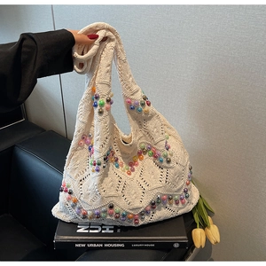 Detail of handwoven crochet tote bag with colorful beads held over a vintage book