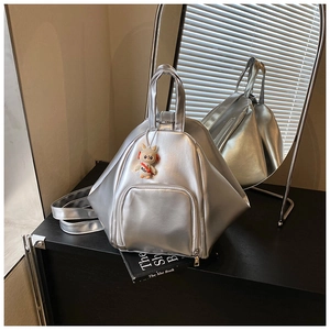 Detailed macro view of geometric silver metallic backpack with astronaut charm and zip