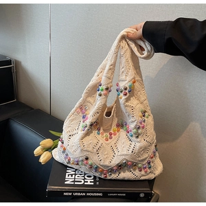 Detailed close-up of beige knitted tote bag with colorful beads and crochet diamond patterns