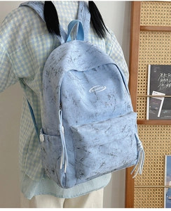 Detail of light blue tie-dye canvas backpack with front zip pocket and side water bottle holder
